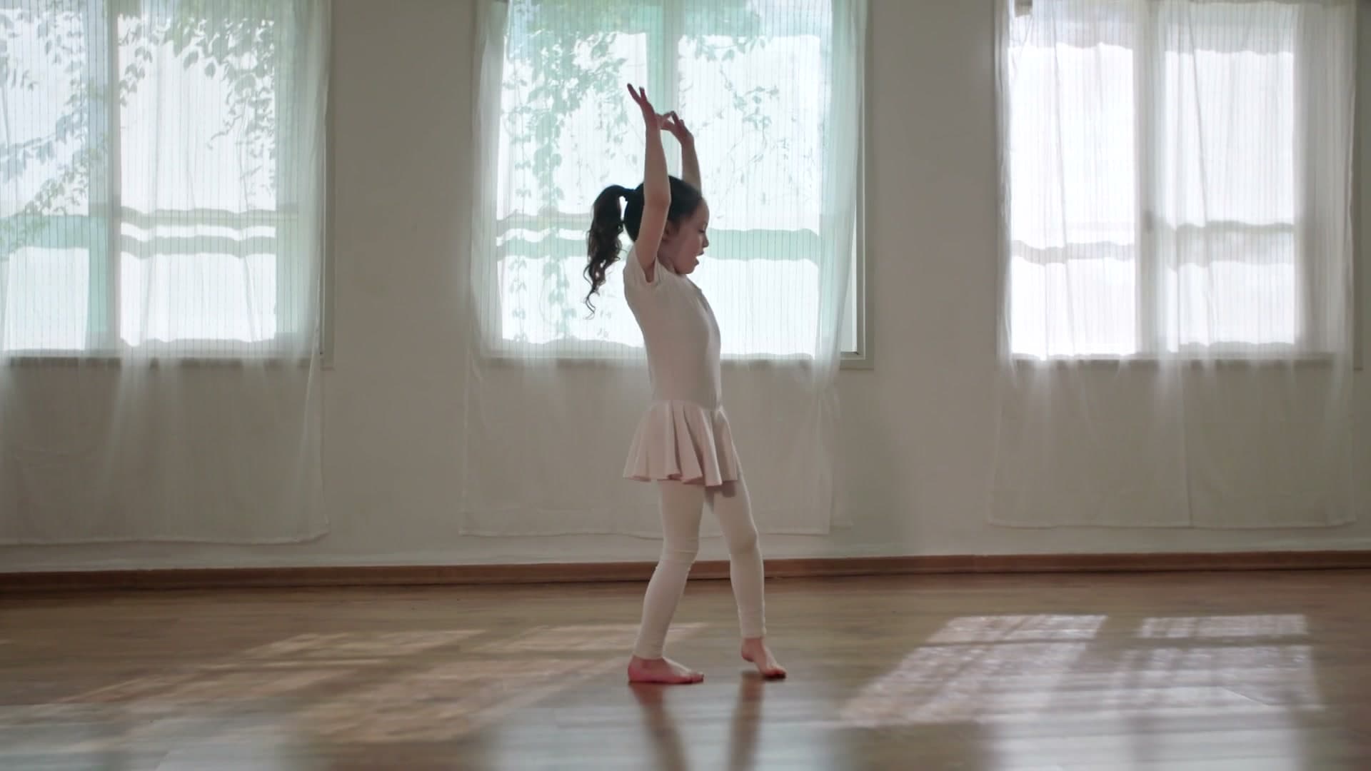 A young ballerina practices in window light
