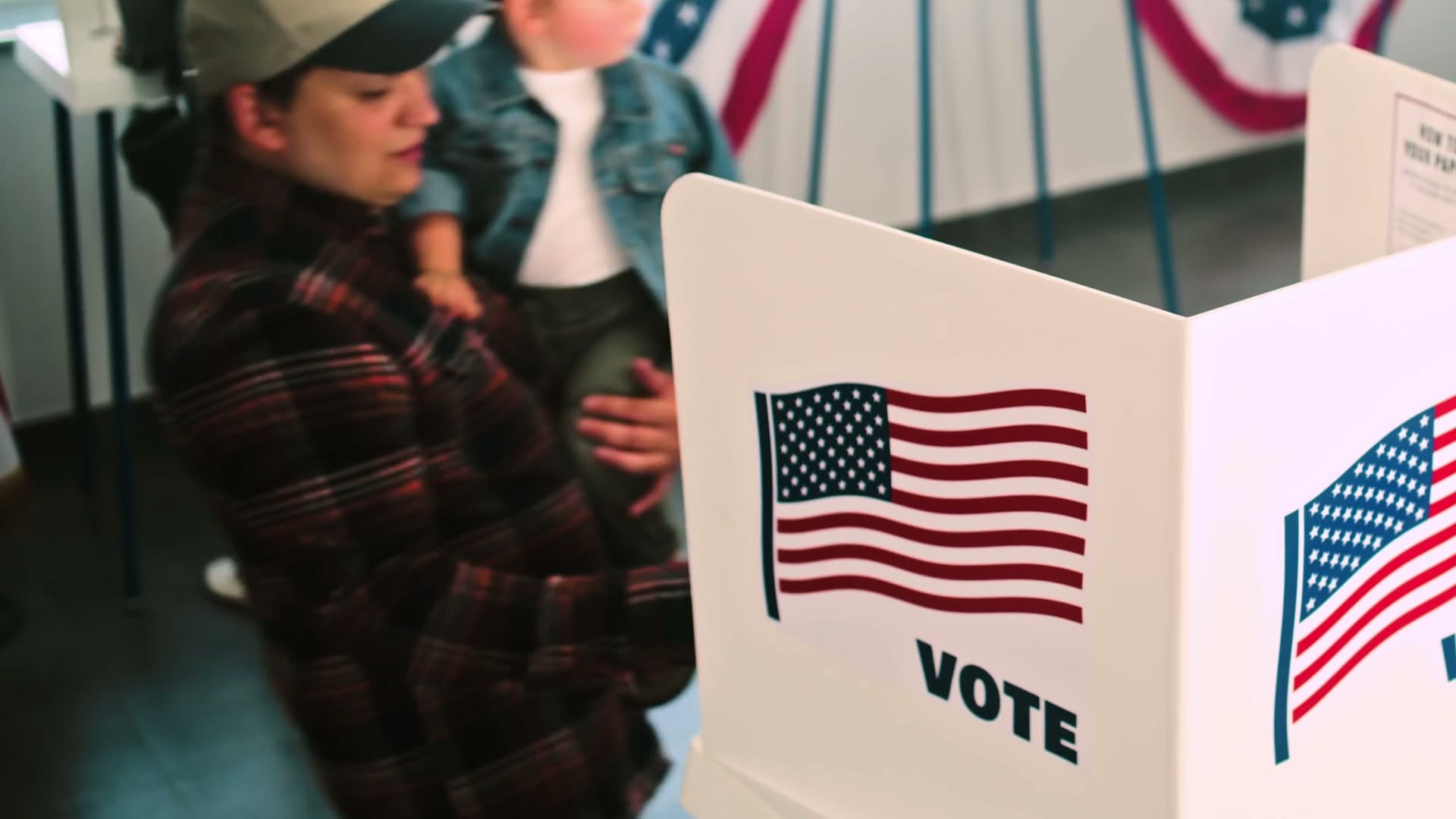 A parent votes with a child at their side